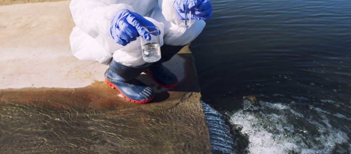 unrecognizable-ecologist-standing-where-sewage-waste-water-meets-the-river-and-taking-samples-to-determine-level-of-contamination-and-pollution-1-1024x683